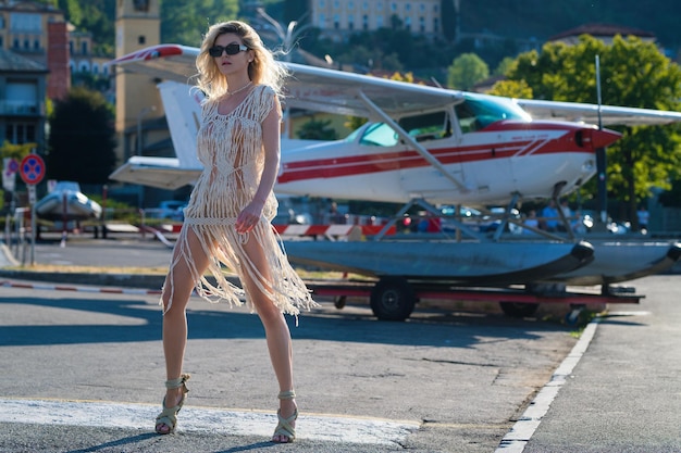 Mode junge Frau in stylischem Kleid, die in der Nähe von Jet-Frauen-Touristen spazieren geht, die aus dem Jet-Flugzeug-Summ aussteigen