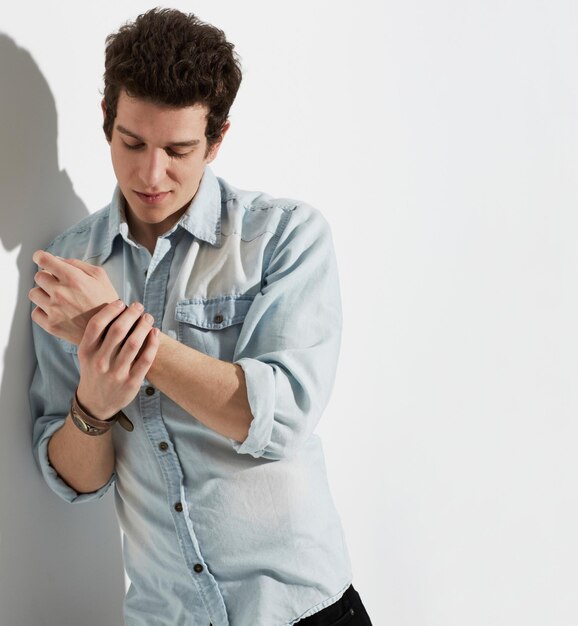 Mode-Mann und stilvolle Kleidung im Studio auf einem Mockup-Raum isoliert auf einem weißen Hintergrund Cool casual und junge Person in Kleidung tragen Armgurt auf der Hand und trendy Model denken auf einem Hintergrund