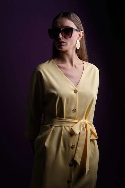 Mode-Modell in der großen Sonnenbrille, die gelbes Kleid mit Knöpfen trägt