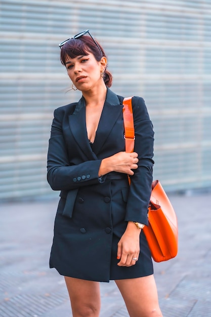 Mode-Pose Brünettes Mädchen in der Stadt mit roter Tasche und moderner Sonnenbrille, die in die Kamera schaut