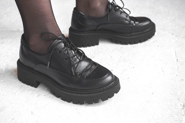 Mode schwarze Stiefel auf weiblichen Beinen. Modell im Studio mit konkretem Hintergrund, urbanes Casual-Design-Konzeptfoto