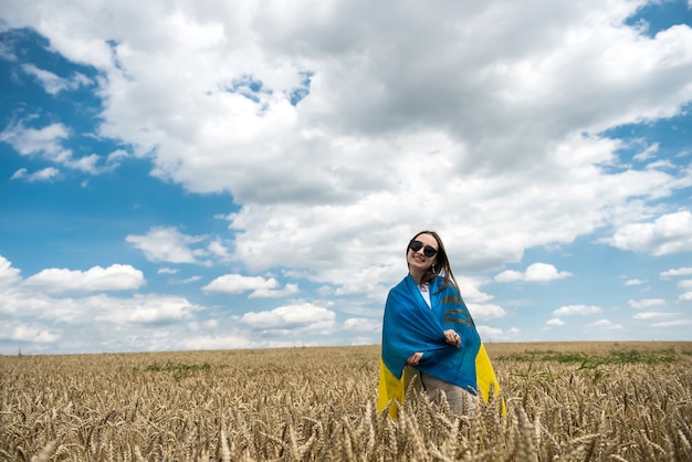 Mode ukrainisches Mädchen mit Nationalflagge auf Weizenfeld im Sommer