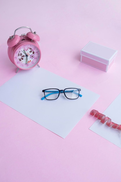 Mode- und Schönheitskonzept, das flach mit quadratischen Brillen Damenaccessoires auf rosa Hintergrund liegt