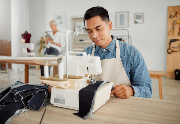 Modedesign und Stil mit einem jungen Designer, der in einem Startup an einer Nähmaschine in einer Werkstatt arbeitet Vielbeschäftigter und kreativer Designer, der in einem kleinen Unternehmen neue trendige und modische Kleidung kreiert