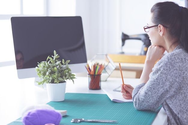 Modedesigner, die im Studio arbeiten, das auf dem Schreibtisch sitzt