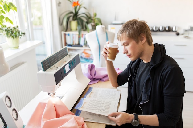 Foto modedesigner mit kaffee und buch im studio