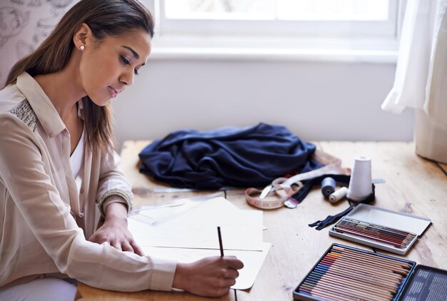 Foto modedesignerin und zeichnerin mit bleistift auf papier im startbüro eines kleinen unternehmens kreativperson oder schneider skizze am schreibtisch zur illustration projektplanung oder schreiben von entwürfen für kleidung