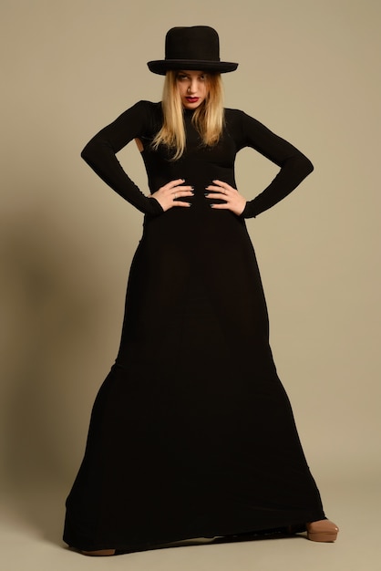 Modefoto der schönen Dame im eleganten schwarzen Kleid und im Hut