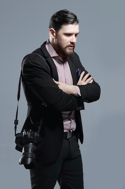 Modefotograf mit einer Kamera mit Blick auf die Seiteisoliert auf grauem Hintergrund