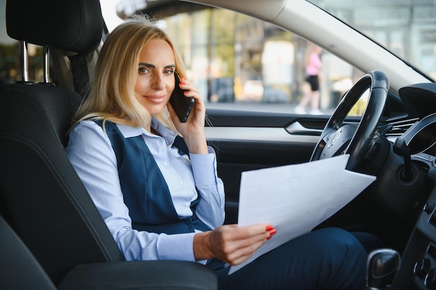 Modegeschäftsfrau mit Finanzpapieren durch ihr Auto