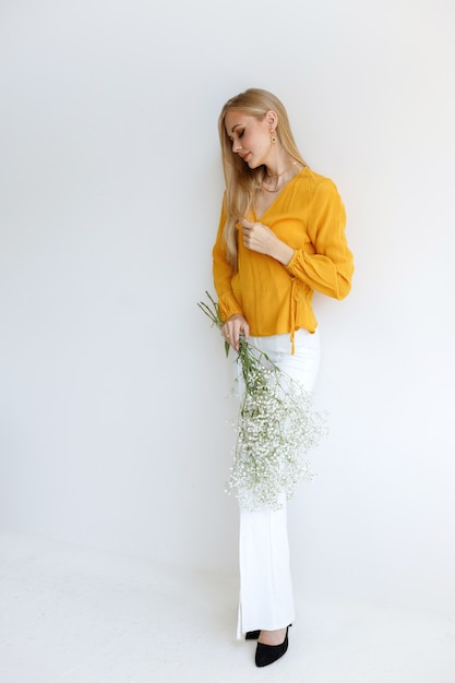 Model Blogger in einem stilvollen Bild mit Blumen auf grauem Hintergrund. Modestimmung