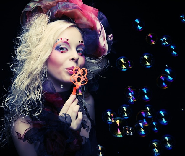 Foto model mit kreativem make-up, das seifenblasen bläst