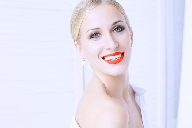 Model mit professionellem Make-up und knallroten Lippen / schönes Make-up im Gesicht des Models, gesättigt mit knallrotem Lippenstift auf den Lippen