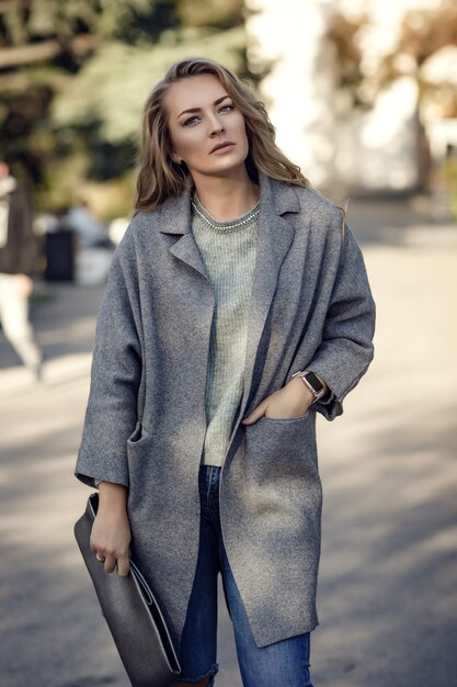 Model mit zerrissenen Boyfriend-Jeans, Jacke und Turnschuhen in der Stadtstraße. Modisches urbanes Outfit