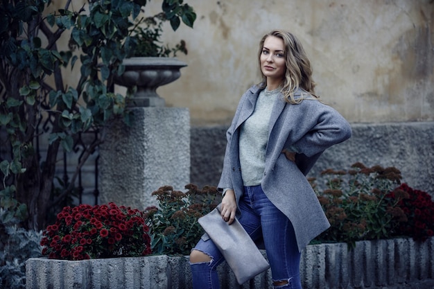 Model mit zerrissenen Boyfriend-Jeans, Jacke und Turnschuhen in der Stadtstraße. Modisches urbanes Outfit