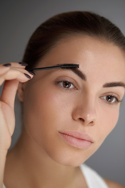 Foto modelado de cejas. retrato de niña hermosa con lápiz de cejas. primer plano de mujer joven con maquillaje profesional