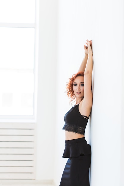 Modelado, concepto de personas - Mujer joven atractiva posando junto a la pared.