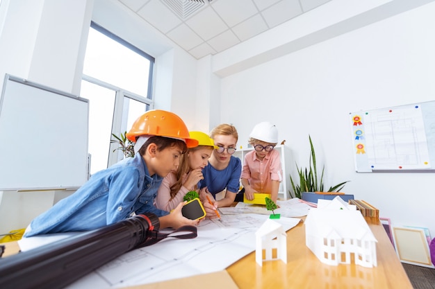 Modelagem de cidade inteligente. crianças usando capacetes brilhantes construindo e modelando uma cidade inteligente com o professor