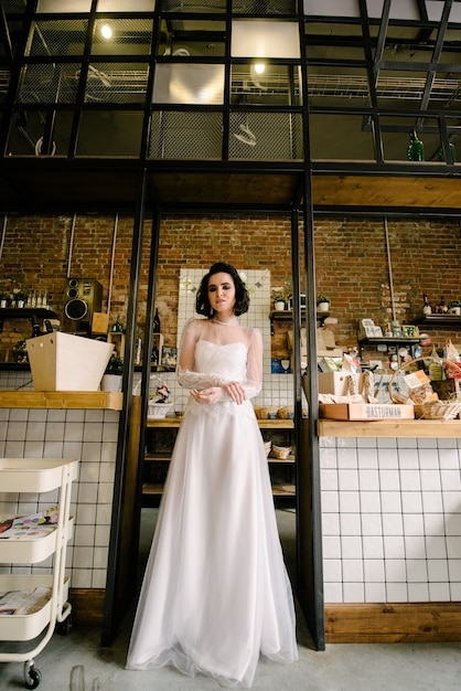 Modell Brünette in kurzen Haaren posiert in einem weißen Hochzeitskleid