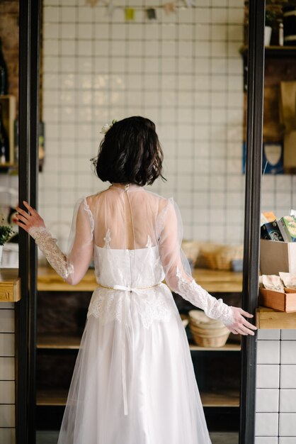 Modell Brünette in kurzen Haaren posiert in einem weißen Hochzeitskleid