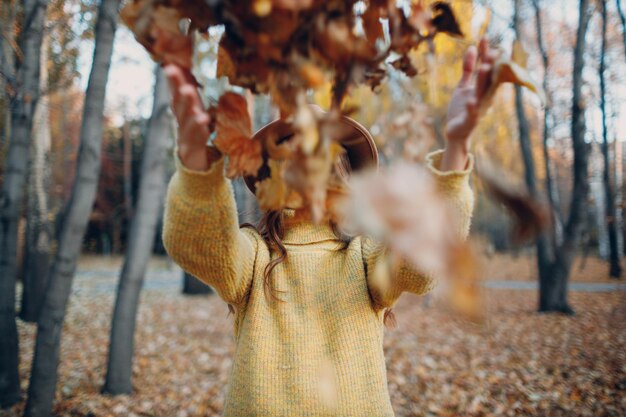 Modell der jungen Frau im Herbstpark mit gelben Laubahornblättern Mode für die Herbstsaison