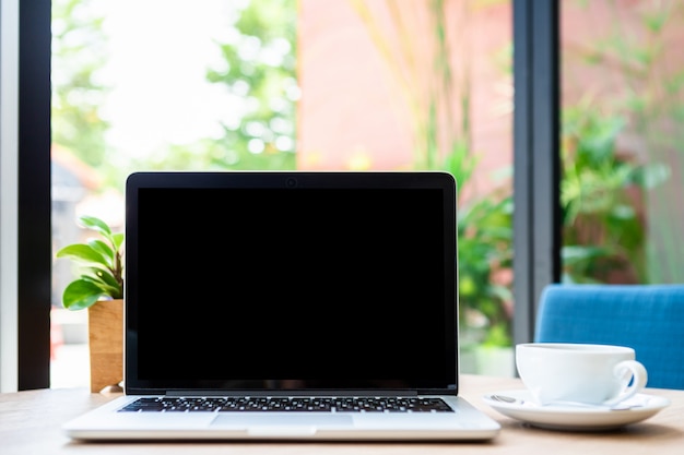 Modell des Laptop-Computers mit leerem Bildschirm mit Kaffeetasse auf Tisch des Coffeeshops, schwarzer Bildschirm