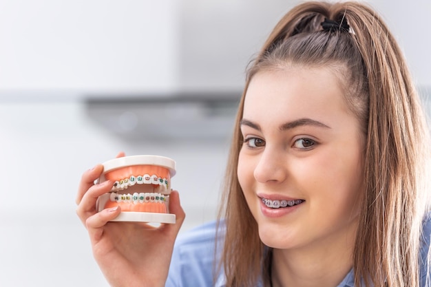 Modell einer Zahnspange in der Hand eines jungen Mädchens mit ausgerichteten Zähnen