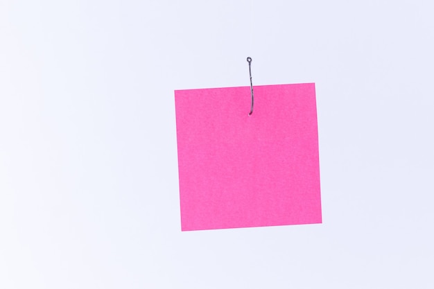 Modell eines leeren rosa Notizpapiers mit Kopienraum, der an einem Angelhaken hängt