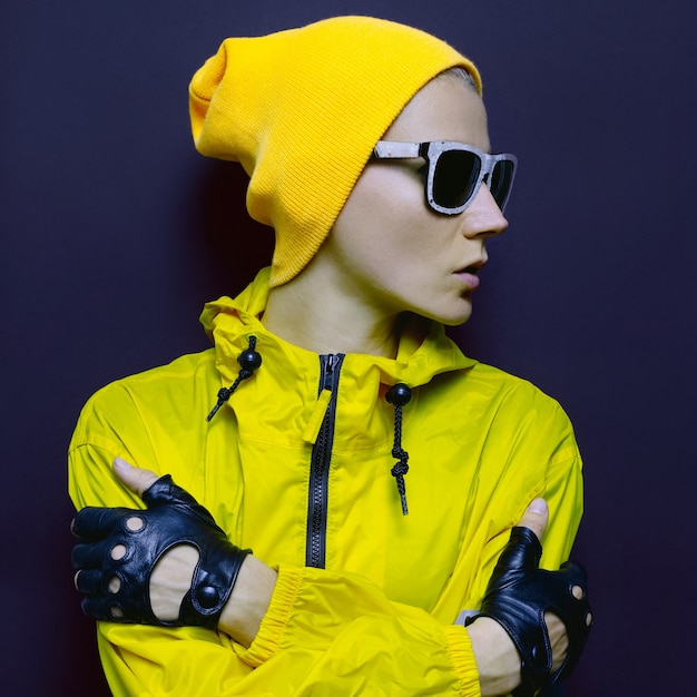 Modell in stylischer gelber Sportbekleidung und Accessoires. Helle Jahreszeit. Snowboard-Mode-Stil