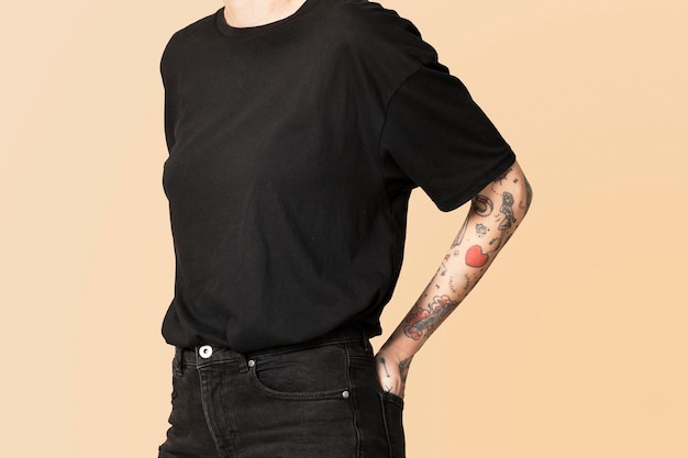 Modell mit Tattoo in schwarzem T-Shirt und Jeans