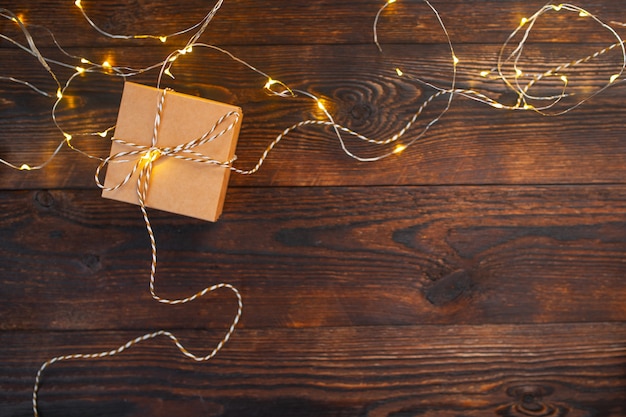 Modell-Weihnachtskraftpapier-Geschenkbox mit Weihnachtsgirlande auf hölzernem