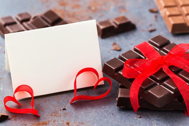 Foto modell zum valentinstag. schokolade mit einem roten band und einer leeren grußkarte gebunden