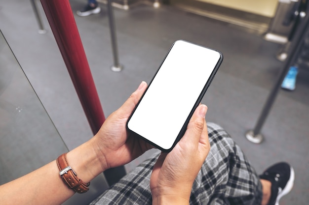 Modellbild der Hände einer Frau, die ein schwarzes Handy mit leerem Bildschirm in der U-Bahn halten