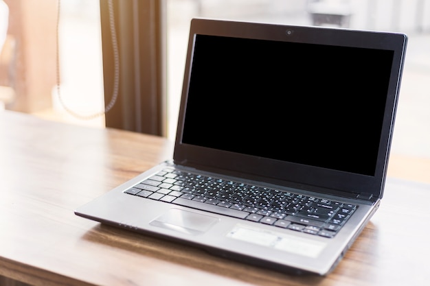 Foto modellbild des laptops mit leerem weißem schirm auf holztisch von in der kaffeestube