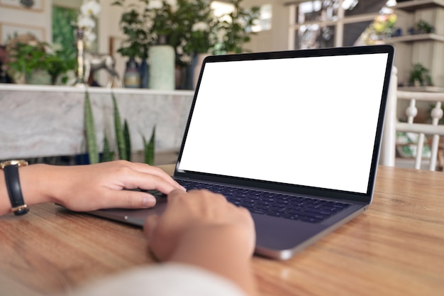 Modellbild einer Frau, die auf Laptop mit leerem weißen Bildschirm auf Holztisch verwendet und tippt