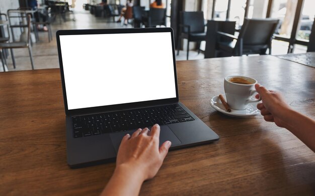 Modellbild einer Frau, die beim Kaffeetrinken ein Laptop-Touchpad mit einem leeren weißen Desktop-Bildschirm verwendet und berührt