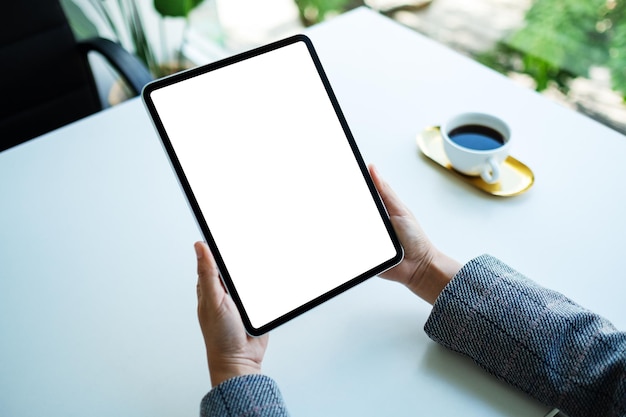 Modellbild einer Frau, die ein digitales Tablet mit einem leeren weißen Desktop-Bildschirm im Büro hält