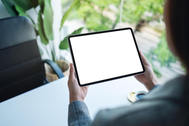 Modellbild einer Frau, die ein Tablet mit einem leeren weißen Desktop-Bildschirm im Büro hält