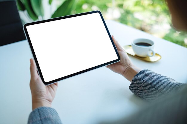 Modellbild einer Frau, die einen Tablet-PC mit einem leeren weißen Desktop-Bildschirm im Büro hält