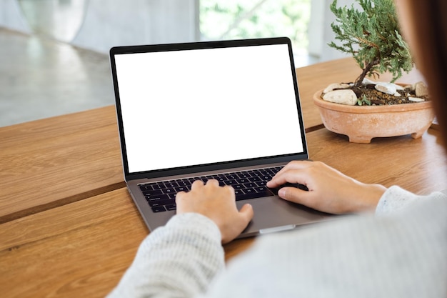 Modellbild einer Frau, die Laptop mit leerem weißem Desktop-Bildschirm auf Holztisch verwendet und tippt