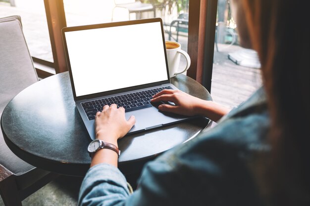 Modellbild einer Frau, die Laptop mit leerem weißem Desktop-Bildschirm mit Kaffeetasse auf dem Tisch verwendet und tippt