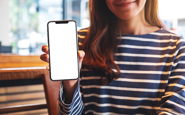 Foto modellbild einer schönen asiatischen frau, die ein mobiltelefon mit leerem weißem bildschirm hält und zeigt