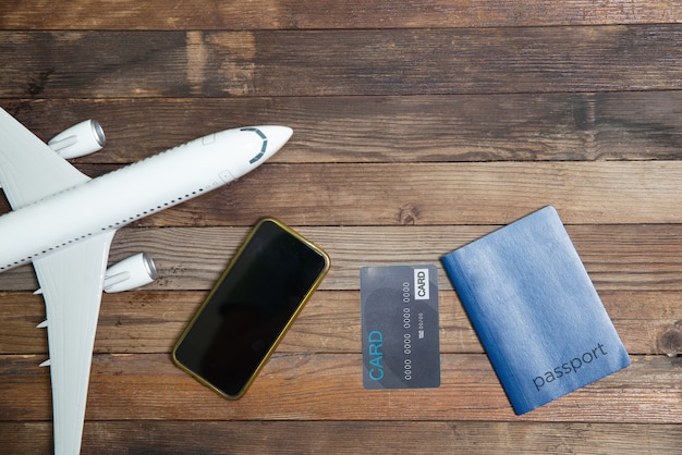 Modellflugzeug, Karte, Smartphone und Reisepass auf einem hölzernen Hintergrund