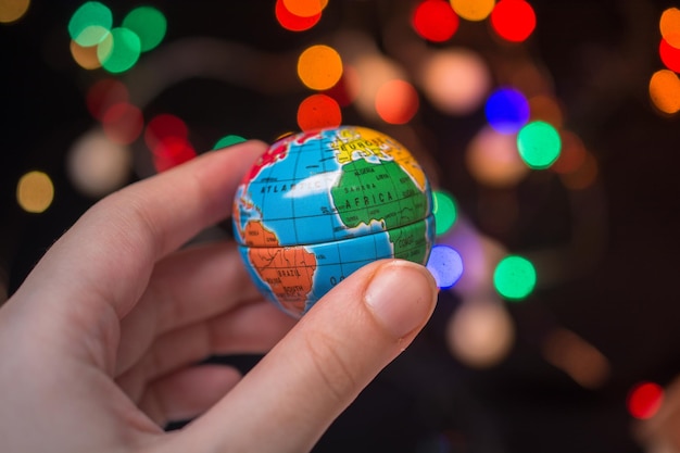 Modellglobus des Planeten Erde in der Hand auf hellem Bokeh-Hintergrund Erhaltung der Umwelt
