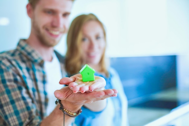 Foto modellhaus in der hand eines paares, das in einem neuen zuhause steht