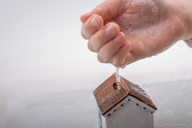 Modellhaus in der Hand in schäumendem Wasser