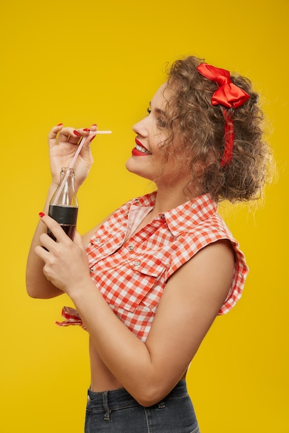 Modellieren Sie mit der perfekten Frisur, die Flasche mit Getränk hält.