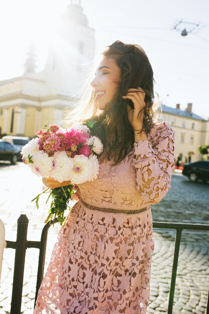 Modelo adorável e sorridente em um vestido de renda segurando um buquê de flores