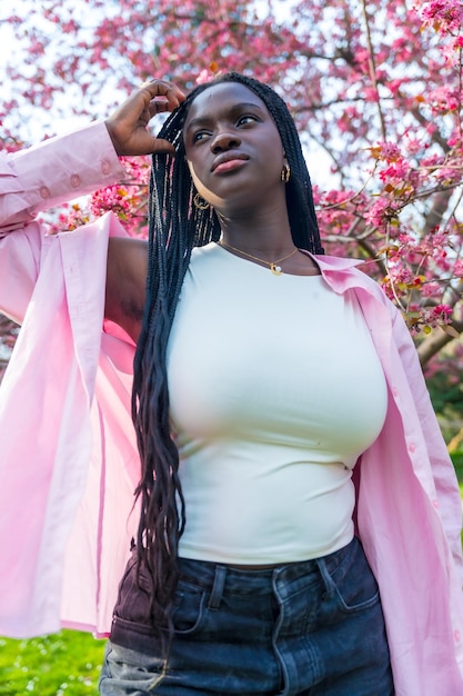 Modelo africano posando junto a un árbol rosado en flor