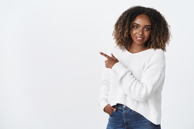 Modelo afro-americano atraente com cabelo encaracolado e suéter branco sorrindo agradavelmente simpático